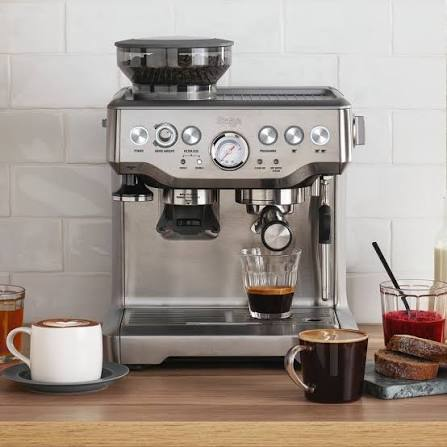 Machine expresso argentée avec réservoir à grains, manomètre et porte-filtre sur un plan de travail